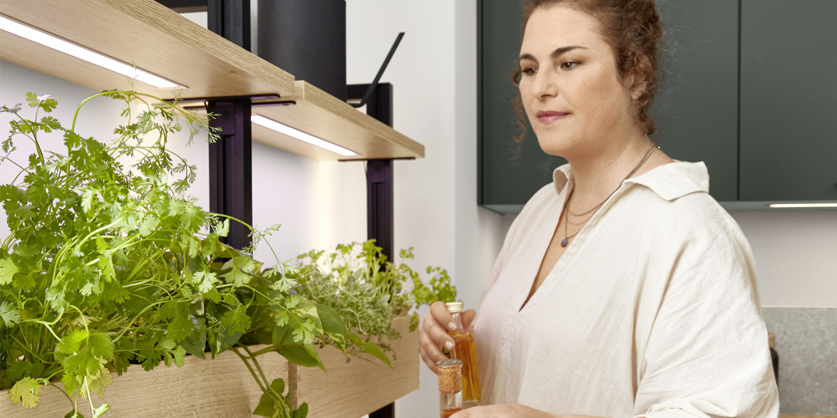 Groener wonen in de stad. Mineraalgroene elementen met grijze accenten geven de keuken een moderne natuurlijkheid. Inclusief een goed idee dat het dagdagelijkse leven in de stad wat duurzamer maakt: het ladesysteem met geïntegreerde plantverlichting plus Gardening Box   thuis telen voor stadsbewoners.