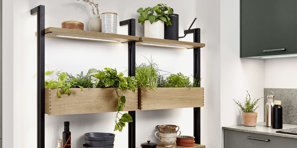 Groener wonen in de stad. Mineraalgroene elementen met grijze accenten geven de keuken een moderne natuurlijkheid. Inclusief een goed idee dat het dagdagelijkse leven in de stad wat duurzamer maakt: het ladesysteem met geïntegreerde plantverlichting plus Gardening Box   thuis telen voor stadsbewoners.